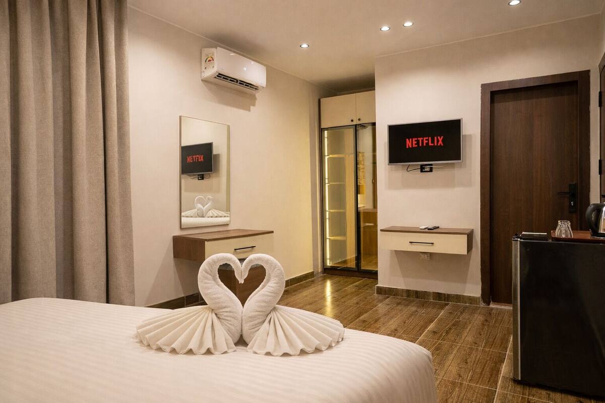 A hotel room with a bed, a TV, a desk, and a wardrobe.