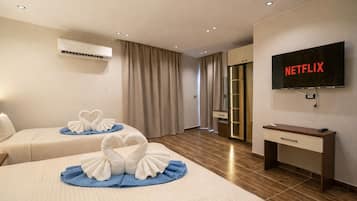 Une chambre d’hôtel avec deux lits, une télévision, un climatiseur et un bureau en bois.