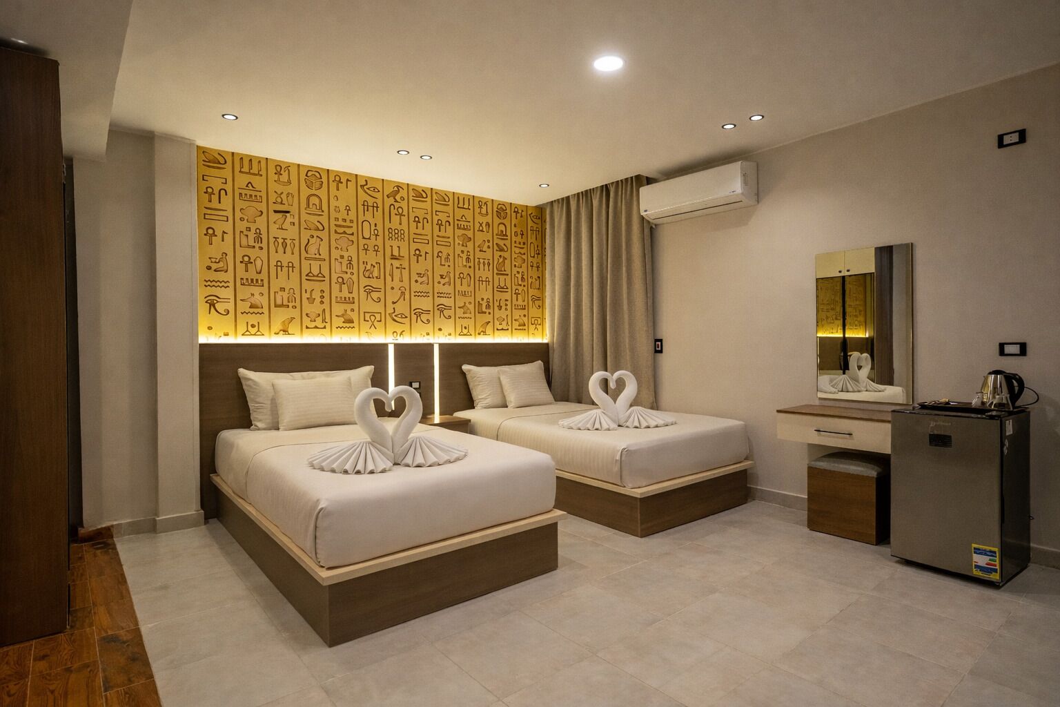 Ein Hotelzimmer mit zwei Betten, einem Schreibtisch und einer Klimaanlage.