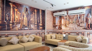 A luxurious living room with Egyptian-themed murals, plush sofas, and a central coffee table.