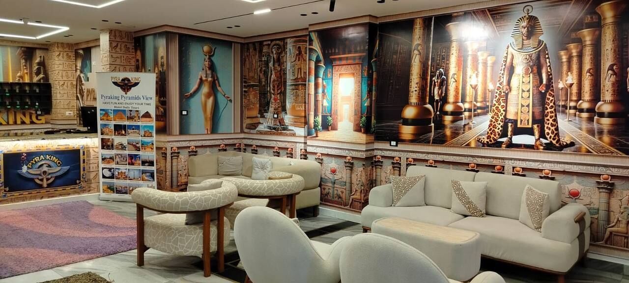 A lobby with a central seating area, a reception desk, and a large mural depicting ancient Egyptian themes.