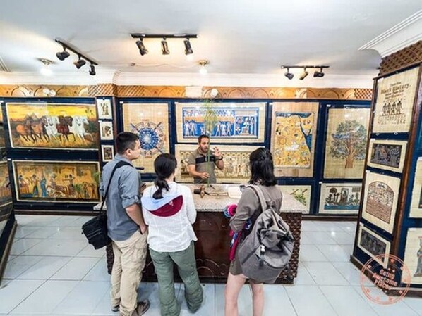 Un groupe de personnes se tient devant un comptoir dans un musée, et diverses œuvres d’art sont exposées sur les murs.
