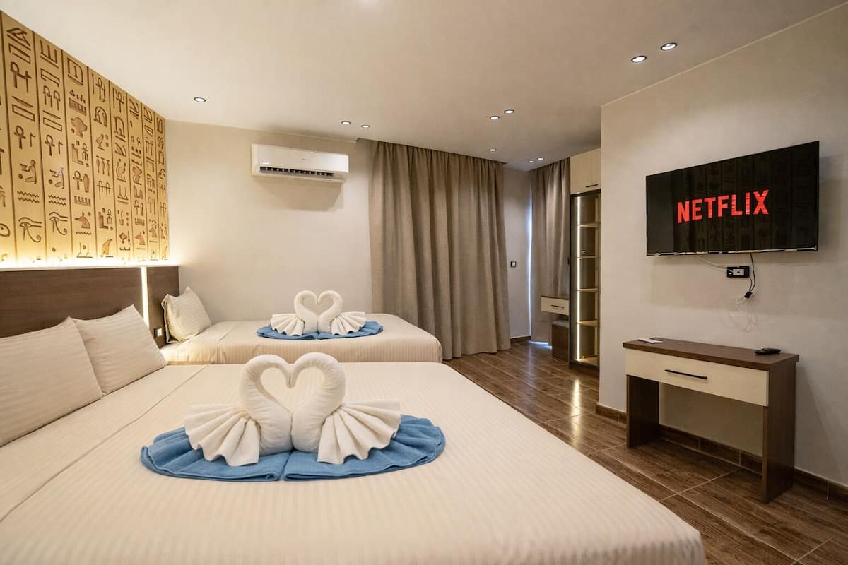 A hotel room with two beds, a TV, and a minibar.