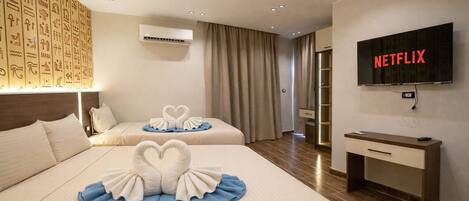 A hotel room with two beds, a TV, and a minibar.