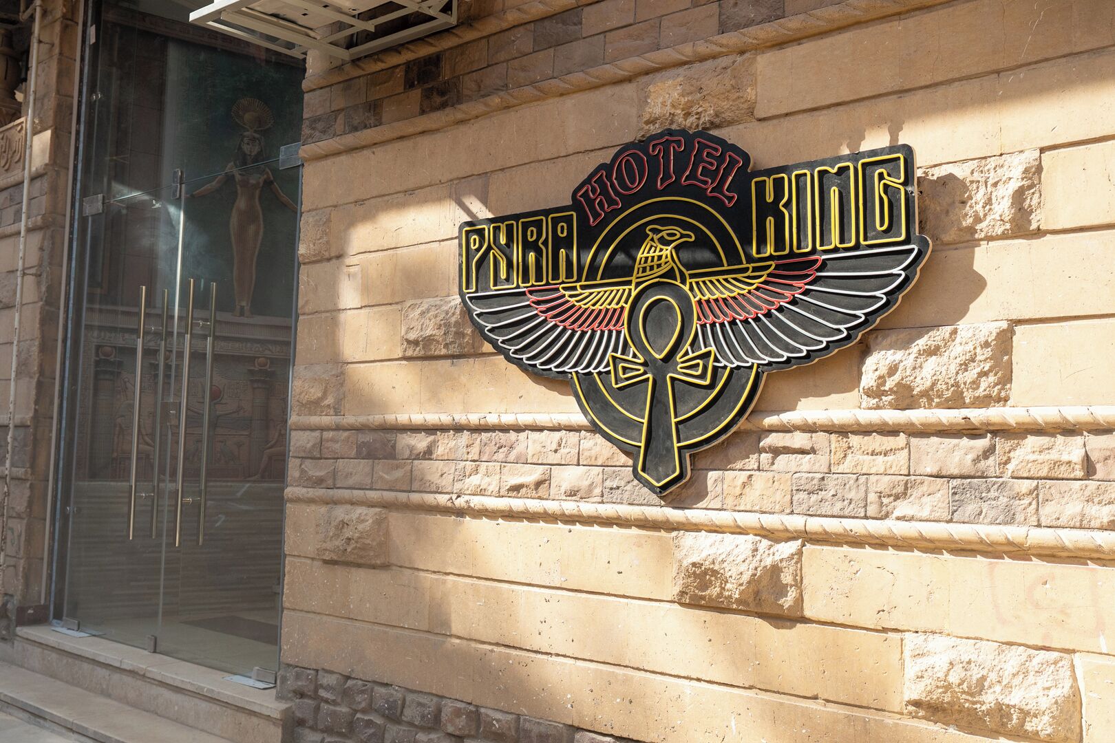Letrero de hotel con un símbolo de ankh alado y el nombre 'Peter King Hotel'.