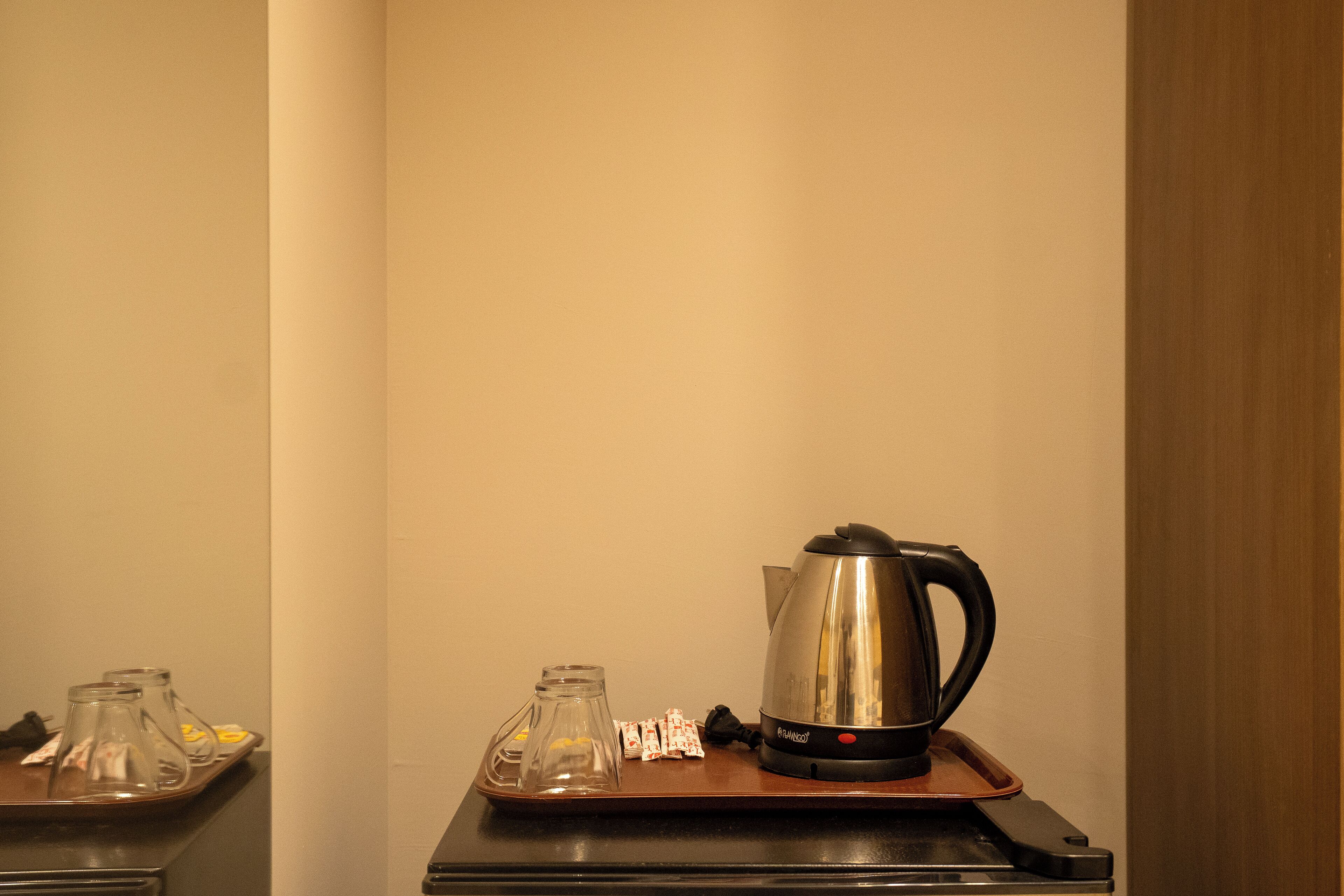 Een koffiezetapparaat op een dienblad met een glazen kan en suikerzakjes.