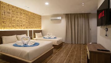 A hotel room with two beds, a TV, and a wall decorated with hieroglyphs.