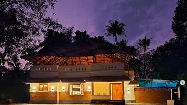A two-story house with a tiled entrance and a well-lit front porch. - Acrewood Farmhouse - Pool Villa (Muvattupuzha)
