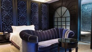 A bedroom with a curved sofa, a glass coffee table, a bed with white linens, and a large arched window. - ALL-UR Boutique Motel Hua-Lian Branch (Hualien)