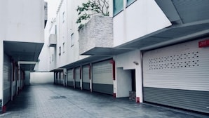 A narrow, paved alleyway between buildings with closed garage doors and a red sign indicating a garage number. - ALL-UR Boutique Motel Hua-Lian Branch (Hualien)