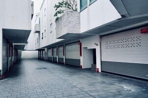 Un estrecho callejón empedrado entre edificios, con puertas de garaje cerradas y un letrero rojo que indica un número de garaje.