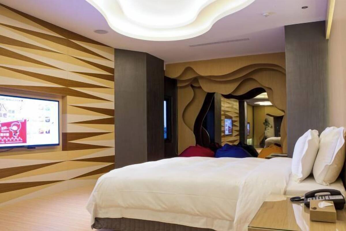 Ein Hotelzimmer im modernen Stil mit einem großen Bett, einem Fernseher und einer außergewöhnlichen Deckenleuchte.