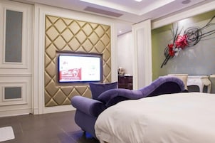 Una habitación de hotel moderna con cama, televisión montada en una pared texturizada y un elemento decorativo en la pared.
