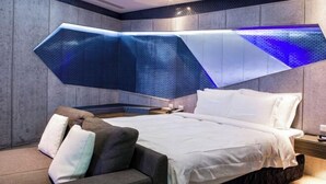 A modern hotel room with a bed, a sofa, and a unique ceiling design. - ALL-UR Boutique Motel Hua-Lian Branch (Hualien)