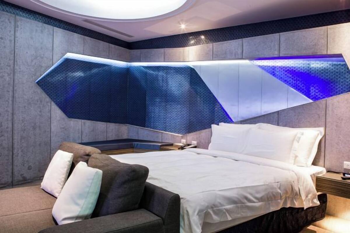 Ein modernes Hotelzimmer mit Bett, Sofa und einem besonderen Design der Decke.