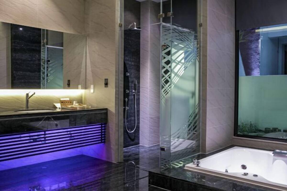 Ein modernes Badezimmer mit einer gläsernen Duschkabine, einem großen Spiegel, einer Badewanne und einem Waschtisch mit Marmorplatte.