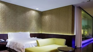 A hotel room with a bed, a yellow sofa, a small round table, and a large window with curtains. - ALL-UR Boutique Motel Hua-Lian Branch (Hualien)