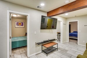 A compact room with a bed, a desk, a TV mounted on the wall, and a door leading to another room. - Explore LA & Long Beach: Compton Condo w/ Patio (Compton)