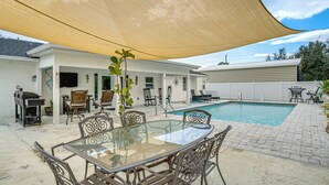 A backyard with a glass table and chairs, a barbecue, and a swimming pool. - Fish, Swim & Boat: Riverfront Port Charlotte Home (Port Charlotte)