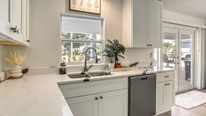 A modern kitchen with white cabinets, a large window, and a dishwasher. - Fish, Swim & Boat: Riverfront Port Charlotte Home (Port Charlotte)
