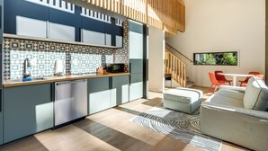 Eine moderne Küche mit einem gemusterten Rückwand, einem eingebauten Geschirrspüler und einem Essbereich mit einer Couch und roten Stühlen.