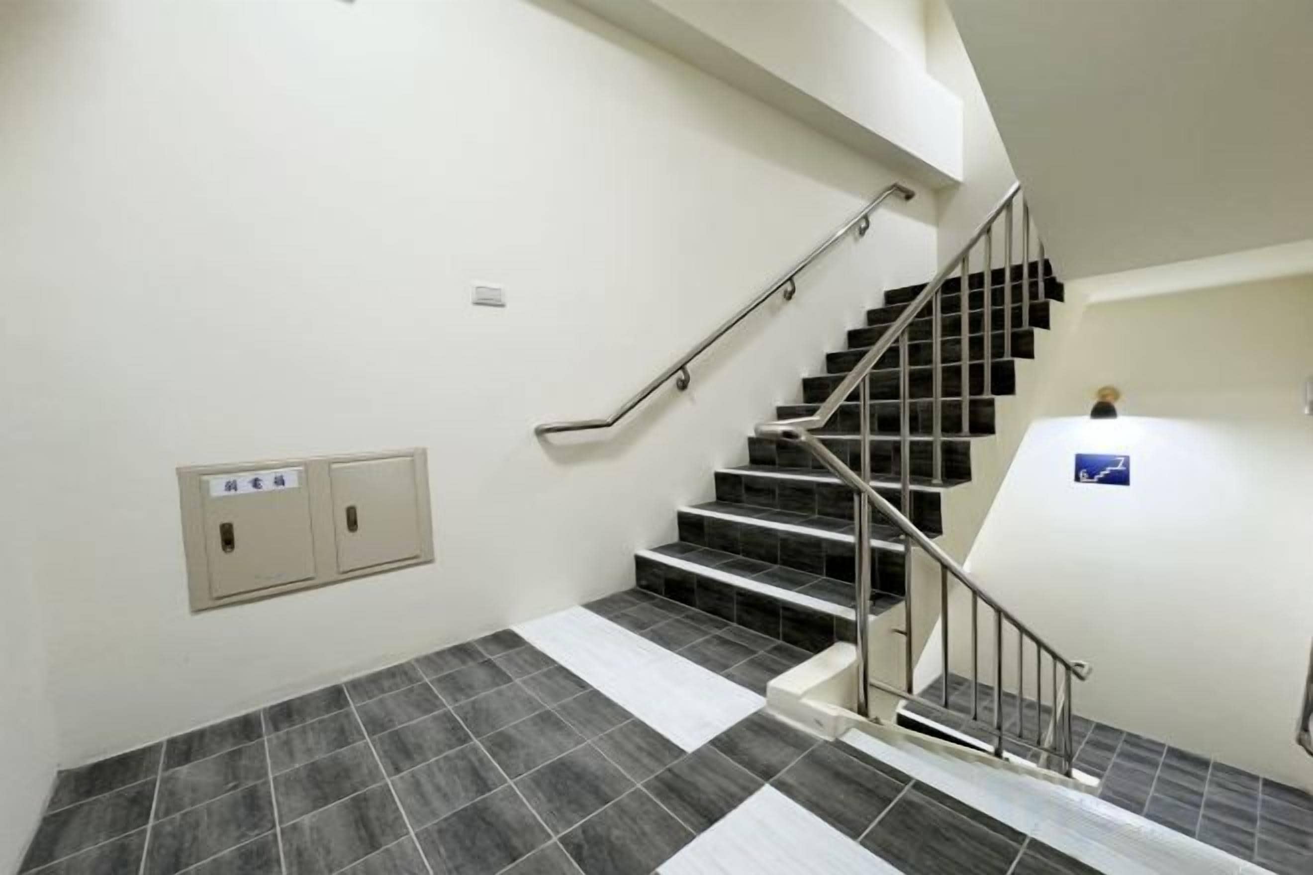 A staircase with a handrail, a wall-mounted intercom, and a fire alarm.