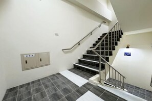 A staircase with a handrail, a wall-mounted intercom, and a fire alarm. - Fengjia Joie de Inn (Taichung)