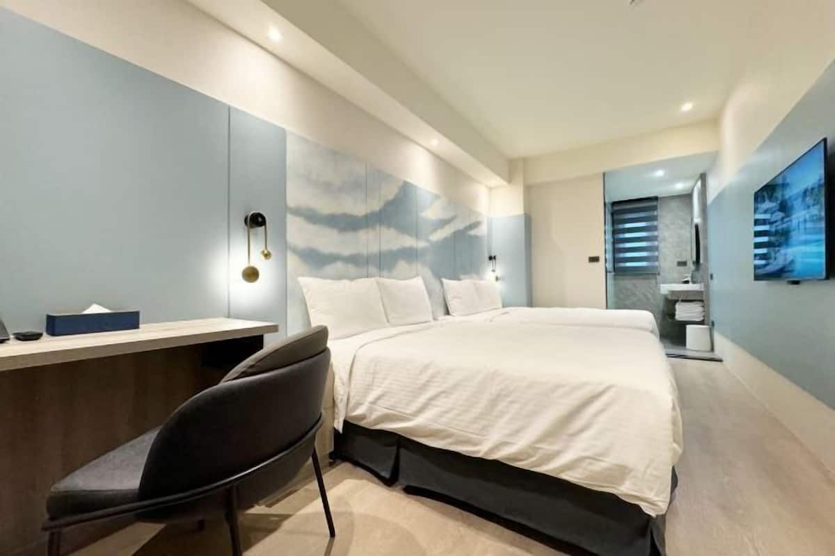 A modern hotel room with a bed, a desk, and a chair.