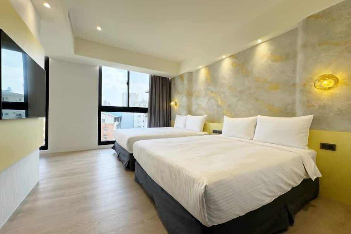 A hotel room with two beds, a large window, and a city view.
