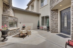A patio area with stone walls, a fireplace, outdoor furniture, and a door. - Mtn-View Patio Oasis! Luxe Family Home in Peoria (Peoria)