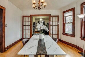 Uma sala de jantar com mesa de mármore, cadeiras de madeira, um vaso com flores e um candelabro.