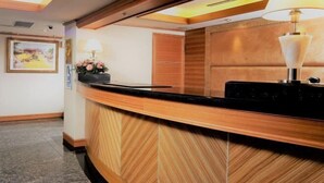 A reception area with a wooden reception desk, a framed picture on the wall, and a lamp on the desk. - Hub Hotel Ximen-Kunming Branch (Taipei)