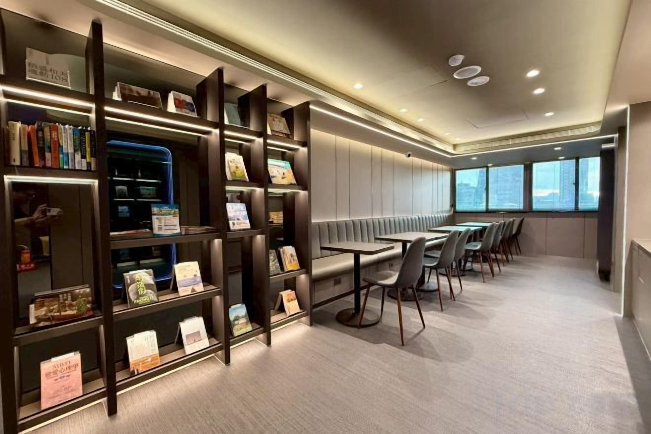 A modern library with bookshelves, a seating area, and large windows.