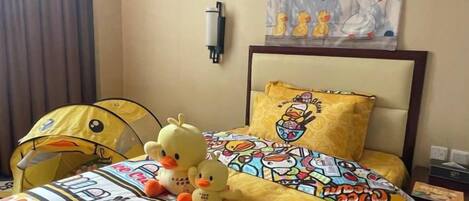 Una habitación de hotel con una cama, una colcha amarilla y una lámpara fijada a la pared.