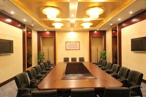 Une salle de conférence avec une longue table, de nombreuses chaises et un écran de télévision.