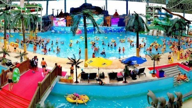 Parque acuático interior con múltiples piscinas, toboganes y atracciones acuáticas.