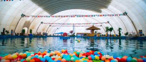 An indoor swimming pool with a large, arched ceiling and colorful floating balls.