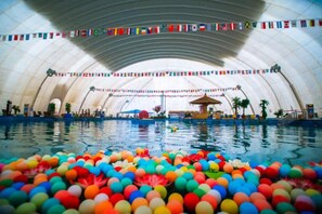 Ein Hallenbad mit einer großen, gewölbten Decke und bunten, schwimmenden Bällen.