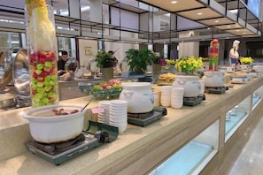 Montaje de bufé con diferentes alimentos y utensilios de servir.
