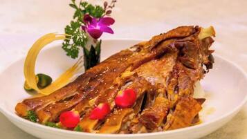 A plate with a cooked fish, garnished with red chili peppers and a decorative flower arrangement.