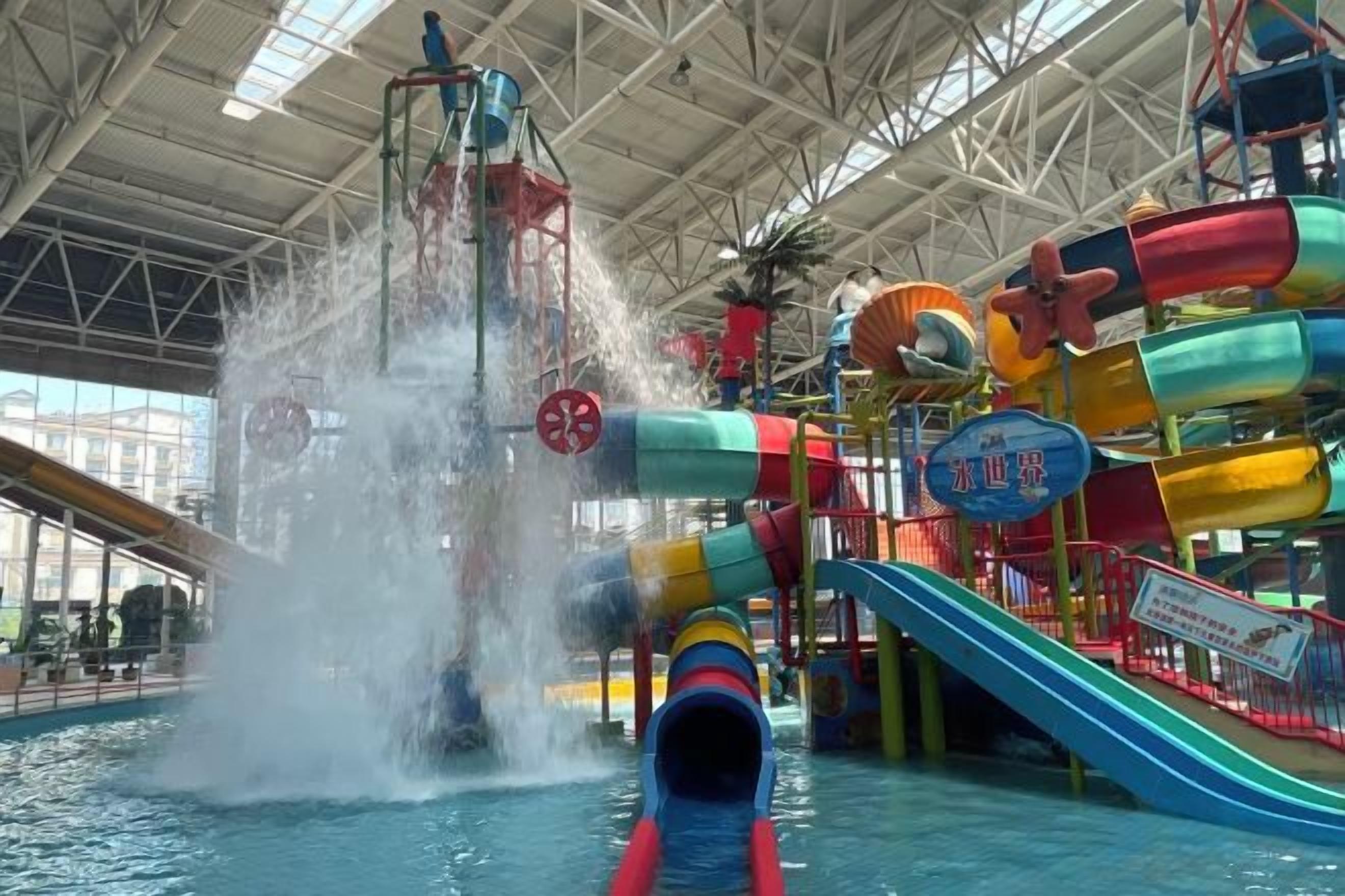 Un parc aquatique intérieur doté d’un toboggan aquatique, de nombreuses structures de jeux et d’une grande piscine.