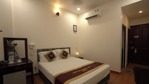 Une chambre d’hôtel comprenant un lit, un bureau avec un miroir, une lampe et un appareil de climatisation.