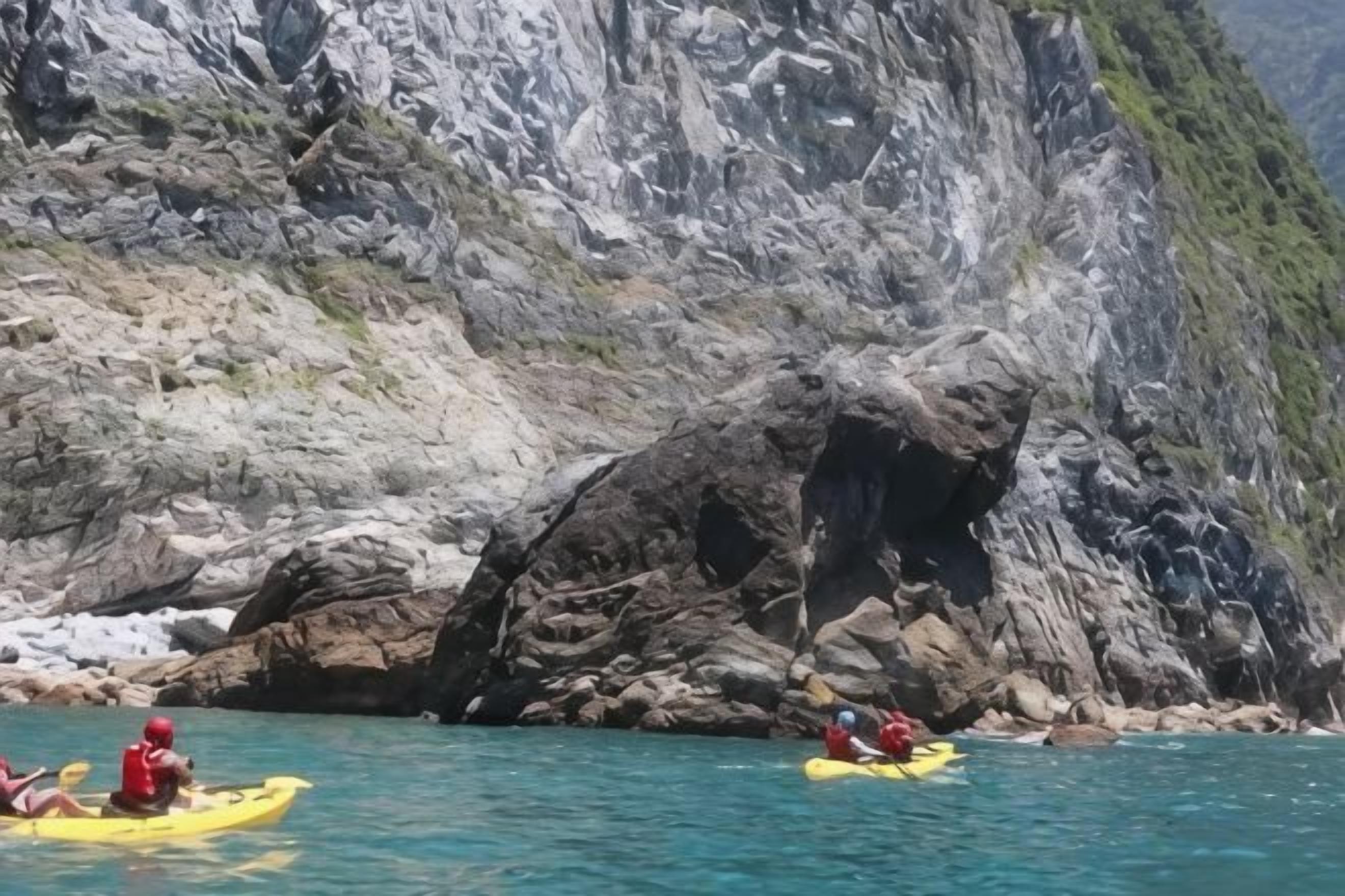 Des kayakistes sur une étendue d’eau calme, avec des falaises rocheuses en arrière-plan.
