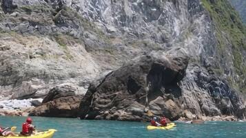 Des kayakistes sur une étendue d’eau calme, avec des falaises rocheuses en arrière-plan.