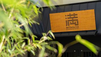 Un letrero de hotel con un logotipo y nombre, indicando que es el Mitsuya Ryokan & Hotel.