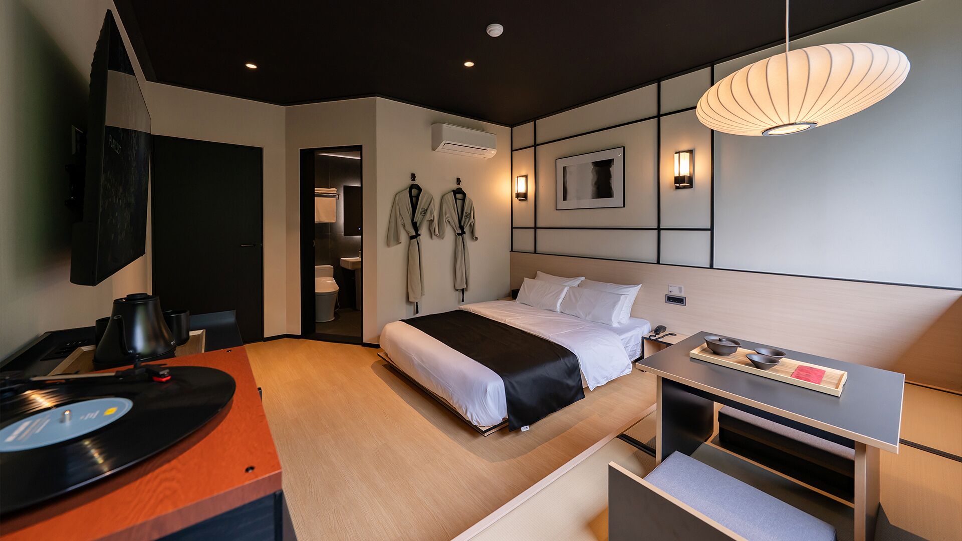 Una habitación de hotel moderna con una cama, un escritorio y un televisor instalado en la pared.