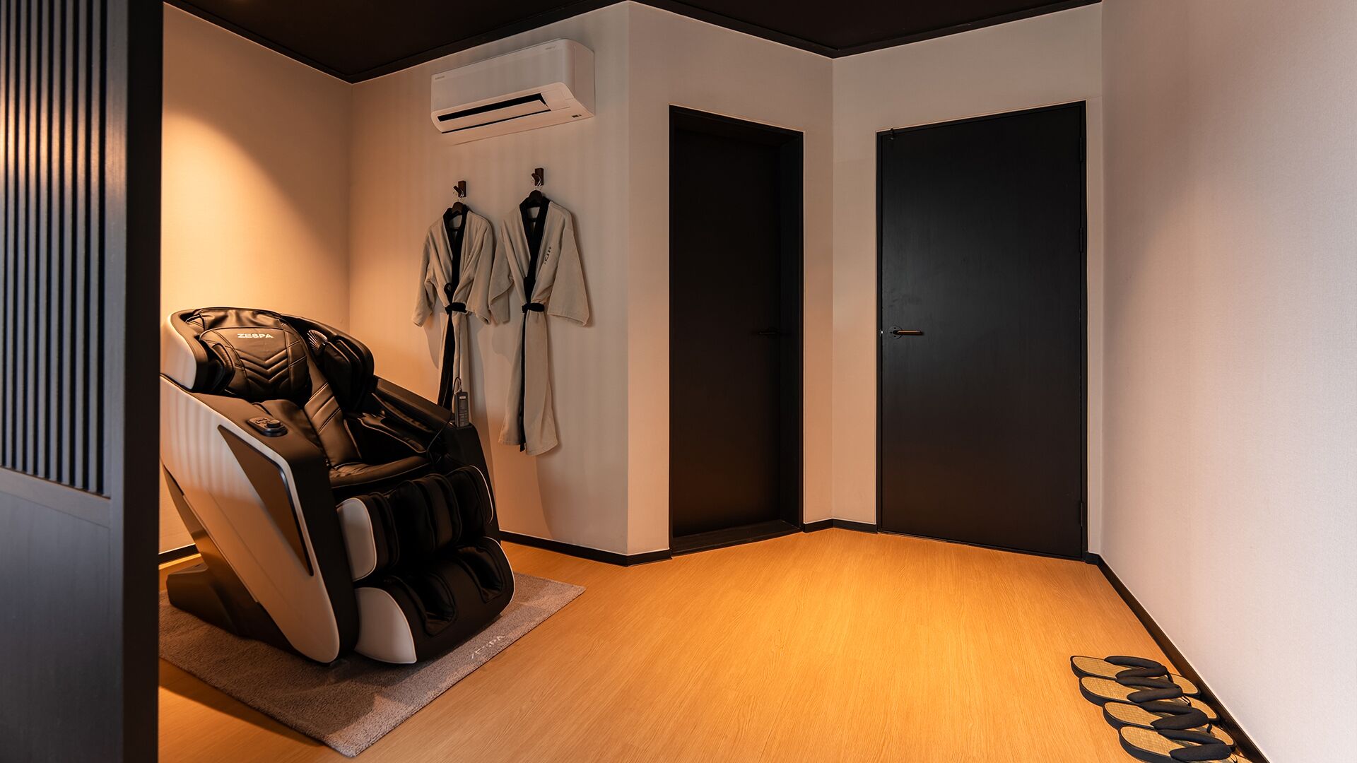 A modern room with a massage chair, a wall-mounted air conditioner, and a door.