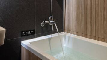 A modern bathroom with a bathtub, a showerhead, and a caution sign.