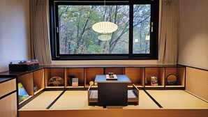 A room with a large window, a tatami mat seating area, a table, and a traditional Japanese lantern. - Mitasuya Ryokan Hotel by Anook Gongju  (Gongju)