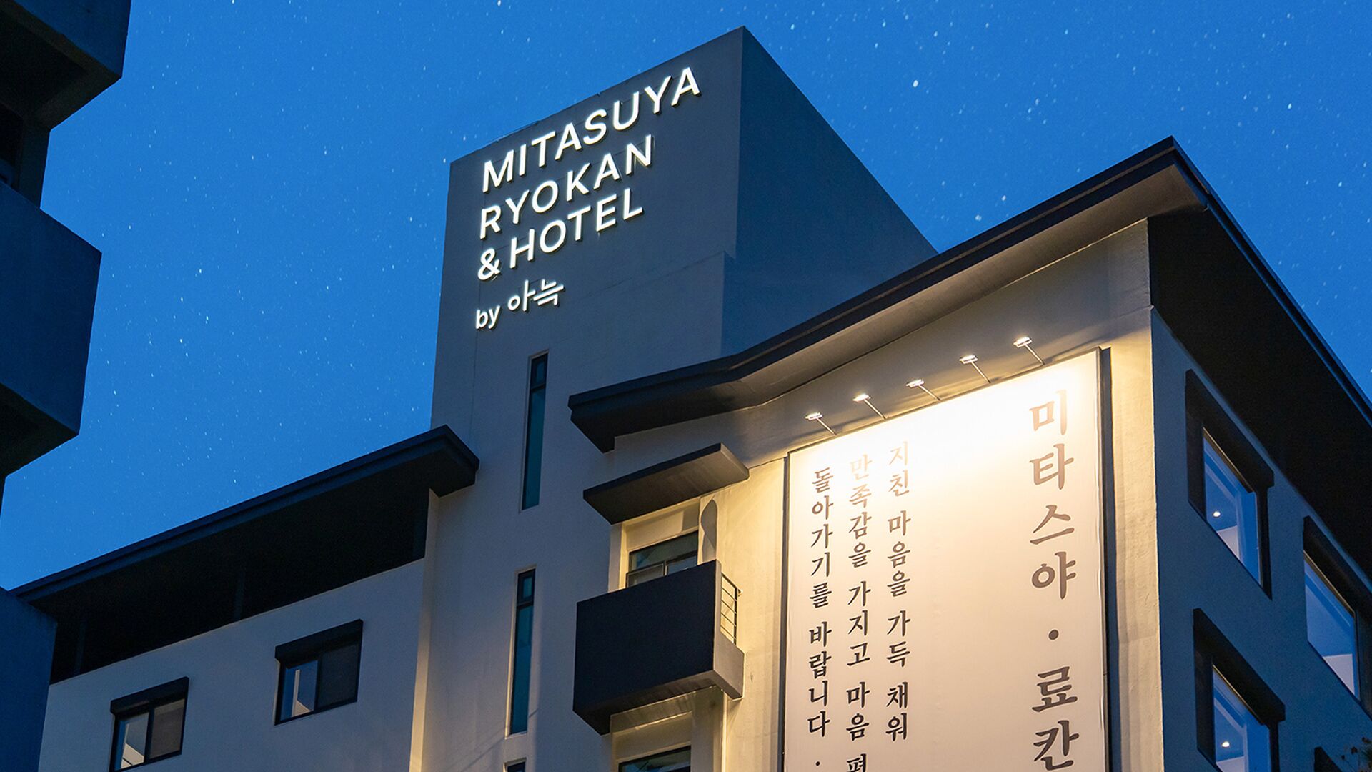 Exterior del Mitsuya Ryokan & Hotel, destacándose un cartel con el nombre del hotel y una entrada de estilo coreano tradicional.